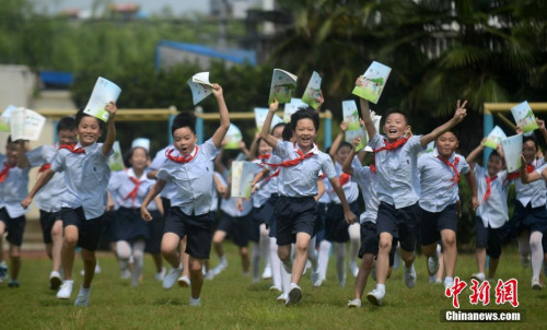 资料图：学生们展示刚刚领到的新学期课本。 孟德龙 摄